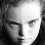 Captivating close-up black and white portrait of a young girl with intense gaze.