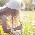 Little girl enjoys picking flowers in a sunlit meadow, embodying pure joy and innocence.