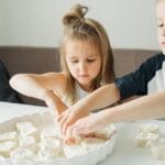 Children enjoying a fun bonding moment as they bake cookies at home.