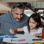A father and daughter enjoying a crafting activity indoors. Creativity and bonding time.