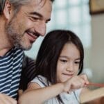 Father and daughter enjoying quality time creating crafts together indoors.