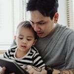 Father and son enjoying quality time using a tablet at home. Capturing a moment of connection.