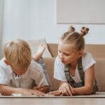 Two children focusing on homework together indoors, fostering sibling togetherness.