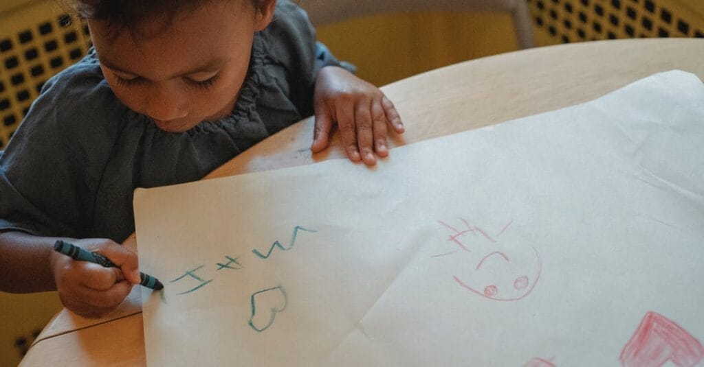 Child drawing with crayons on paper at home, expressing creativity and imagination.