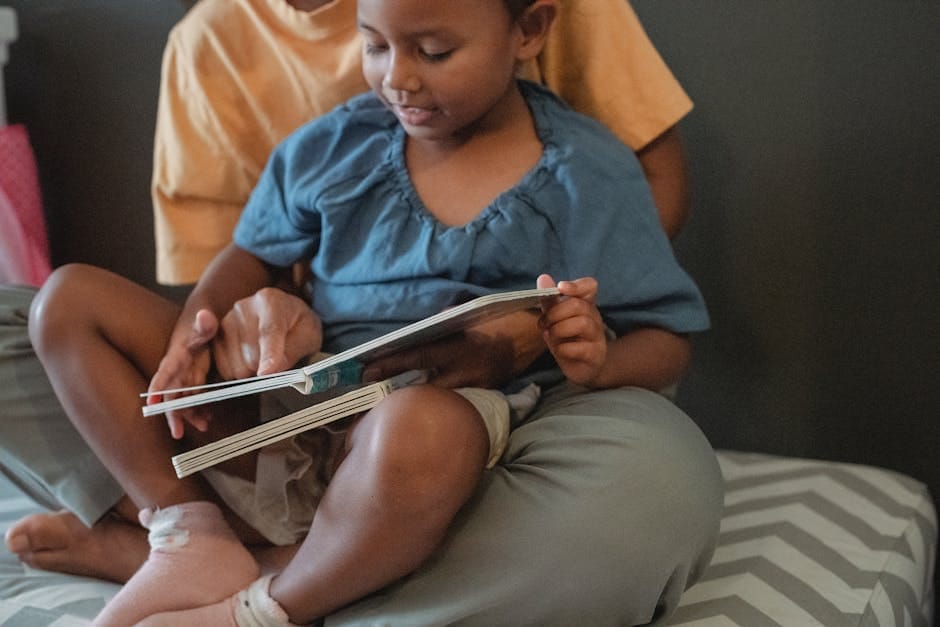 Unrecognizable ethnic mother hugging little girl and reading interesting book while sitting on couch near wall during weekend in apartment