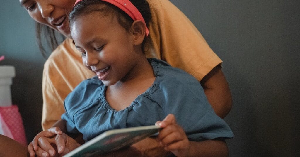 A joyful moment of mother and daughter reading together, sharing stories and smiles at home.
