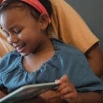 A joyful moment of mother and daughter reading together, sharing stories and smiles at home.