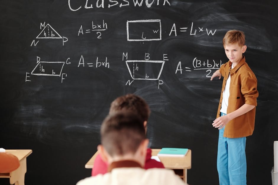 A young student explains math formulas on a blackboard during classwork.