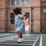 Two girls enjoying a game of hopscotch on a sunny day playground.