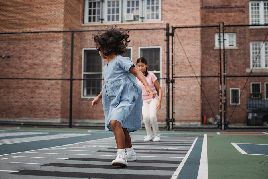 Two girls enjoying a game of hopscotch on a sunny day playground.