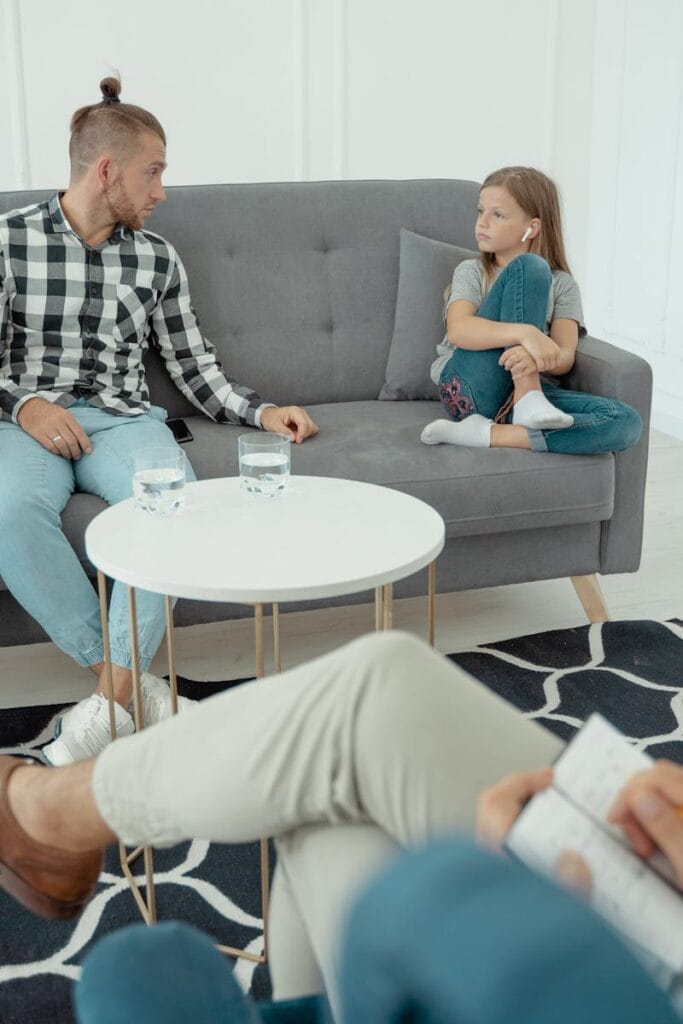 Family therapy session featuring parents and child with therapist in a cozy office setting.