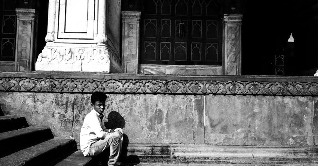 A young boy sitting on historic steps in Delhi, conveying solitude and contemplation.