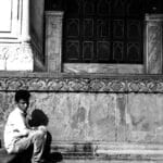 A young boy sitting on historic steps in Delhi, conveying solitude and contemplation.