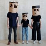 Family wearing cardboard monster masks for Halloween, showing creativity and fun.