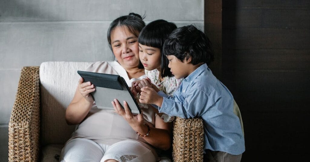 An Asian grandmother spending quality time with her grandchildren, sharing a moment on a tablet.