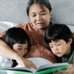 A mother reads a storybook to her two children, creating a cozy and warm bedtime moment.