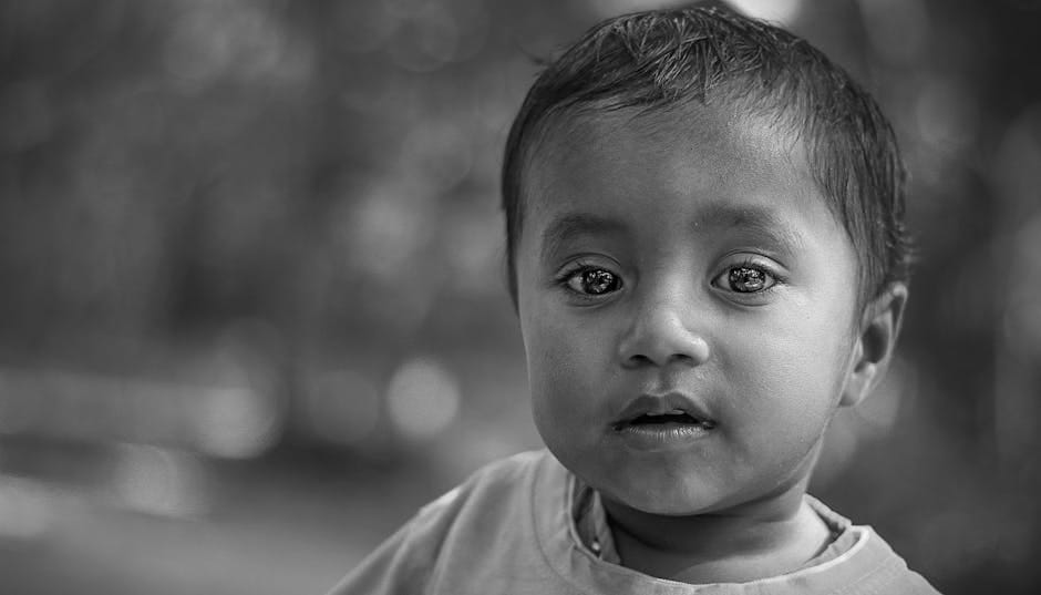 Close-up black and white portrait of a young boy with expressive eyes in soft focus.