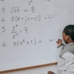 A focused child solves math problems on a classroom whiteboard, demonstrating learning and concentration.