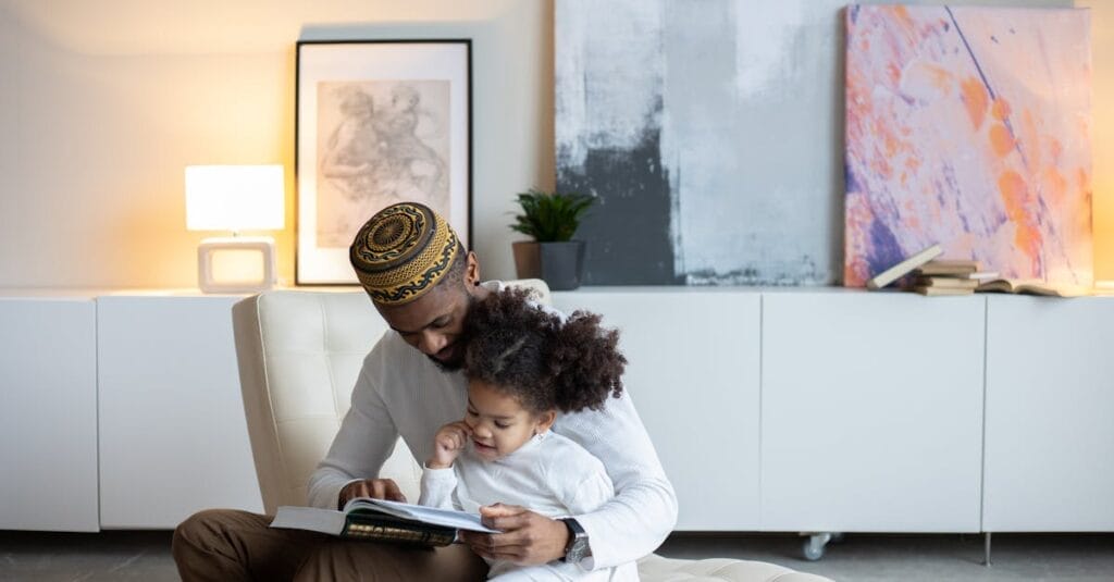 Father and daughter bonding while reading a book indoors, enjoying quality time.