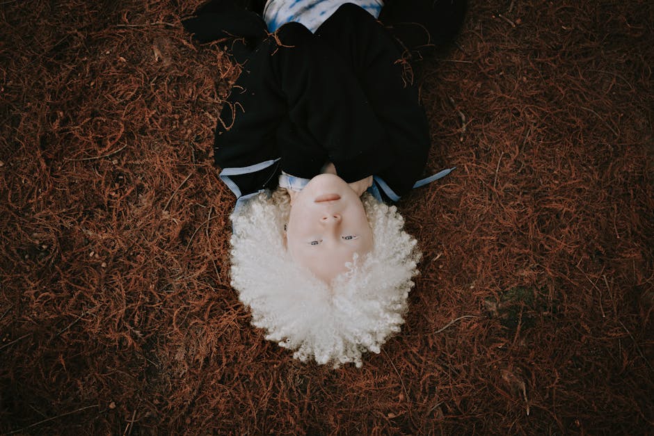 Portrait of an albino child lying on an earthy, natural background, showcasing unique beauty.