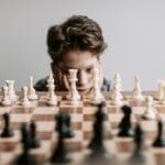 A young boy intensely focused on a chessboard, pondering his next strategic move indoors.