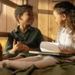 Two children enjoying a cozy reading session indoors, sharing moments of joy.