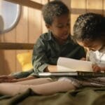 Children reading together in a cozy indoor setting, highlighting warmth and learning.