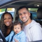 Family of three smiling in a car, showcasing joy and togetherness.