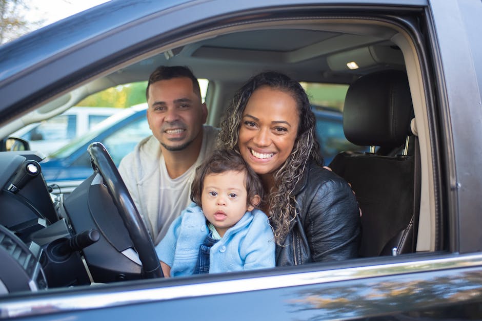 A joyful family with a baby in a car, expressing happiness and togetherness.