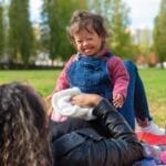 Smiling mother and child with Down syndrome enjoying a picnic in the park.