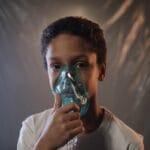 Portrait of a child using an oxygen mask indoors, highlighting health care needs.