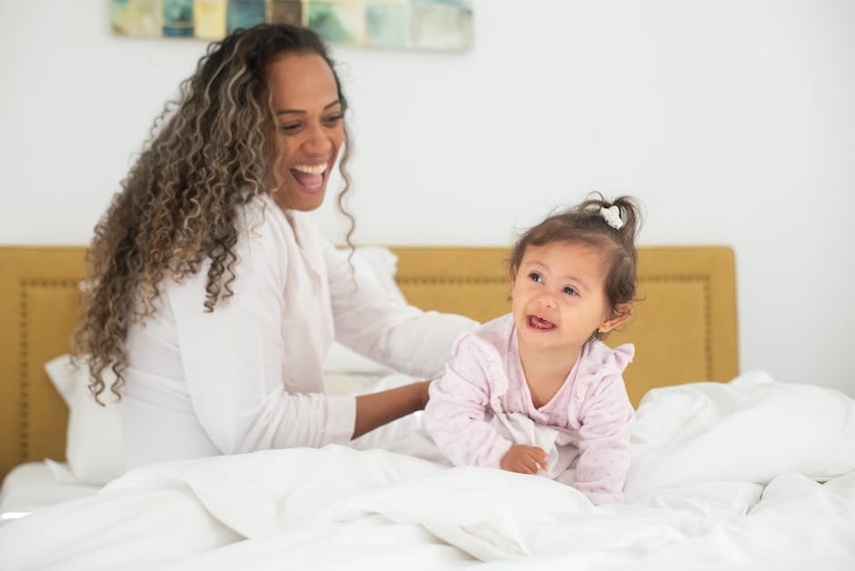 A joyful mother and her baby spending quality time on a cozy bed indoors.