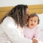 A joyful mother and child sharing a tender moment on a sunny morning indoors.