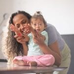 A joyful mother and her child sharing a moment of happiness and affection indoors.