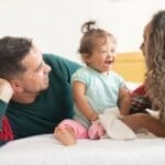 Smiling family enjoying quality time together in a cozy bedroom setting, capturing warmth and love.