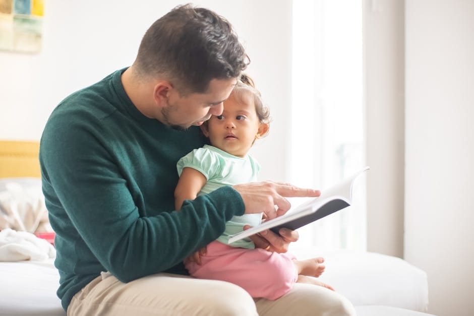 A tender moment as a father reads a book to his young daughter at home.