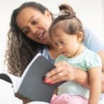 A mother and her young daughter enjoy reading a book together, fostering early learning.