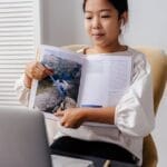 A young girl interacting with an online learning session at home, showcasing technology in education.