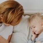 Mother and child bonding on a cozy bed, sharing a comforting and relaxing moment.