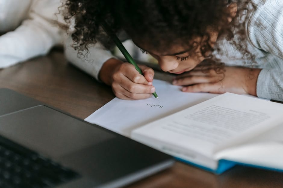 A young girl intently writes with a pencil, surrounded by educational materials at home.