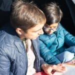 Father and son enjoy quality reading time in a cozy tent outdoors.