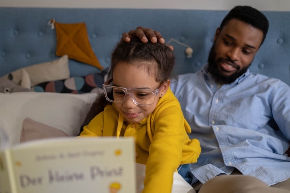A father and daughter share a joyful moment reading on the bed.