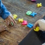 Kids engaging with colorful plastic numbers on a wooden table, fostering early math skills.