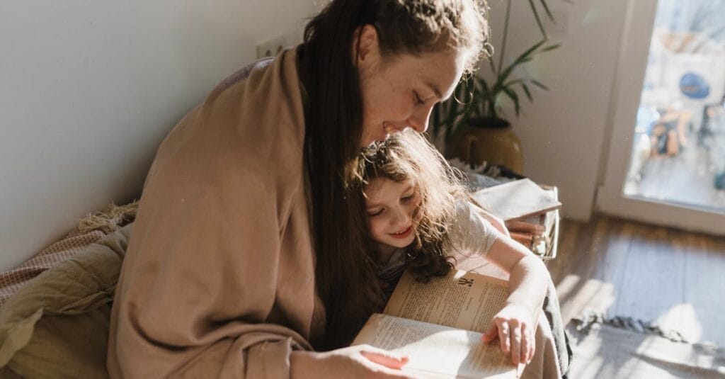 A warm moment of a mother and daughter reading a book by the window.