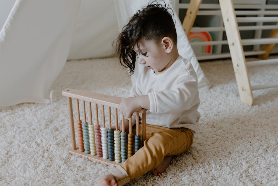 Young child sits on a carpet playing with a colorful wooden abacus in a cozy indoor setting.