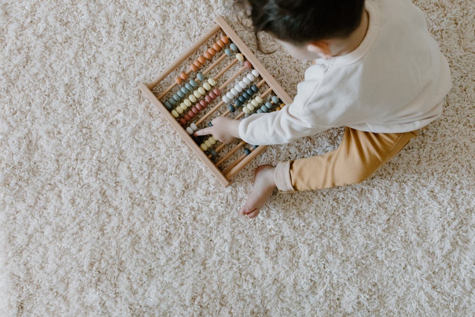 Young child playing with a colorful wooden abacus on a carpet.