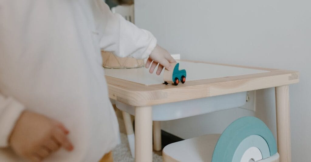 A young child plays with a wooden toy on a small table indoors, showcasing minimalist design.