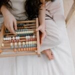 A child using a colorful abacus to learn math in a cozy indoor setting.