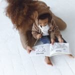 African American mother and young child reading a picture book together, fostering bonding and learning.