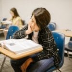 A young student absorbed in reading a book in an educational classroom environment.